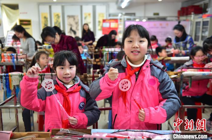 圖為小學(xué)生展示繡制好的2022年北京冬奧會吉祥物“冰墩墩”形象?！∮髟屏?攝