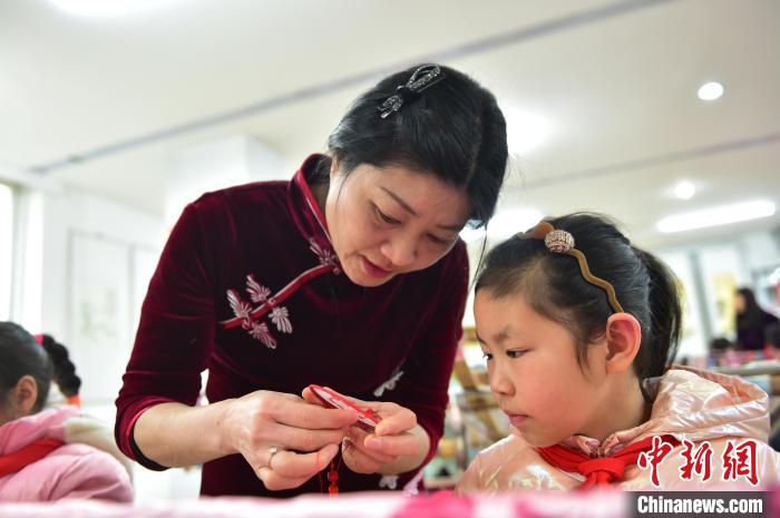 江西省級非遺豫章繡傳承人手把手指導(dǎo)小學(xué)生繡制2022年北京冬奧會吉祥物“冰墩墩”形象。　喻云亮 攝