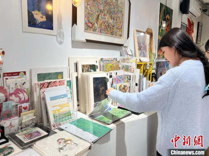 圖為藝術(shù)品商店內(nèi)，顧客挑選插畫作品?！＄婌?攝