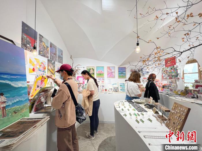 圖為藝術(shù)品商店內(nèi)，顧客挑選插畫作品?！＄婌?攝