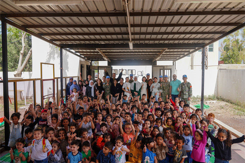 當地時間5月30日，黎巴嫩南部庫雷拉公立小學，“六一”國際兒童節(jié)前夕，中國第21批赴黎維和多功能工兵分隊官兵看望慰問學校師生，并開展文化交流活動，圖為我維和官兵同師生合影。李竹林攝