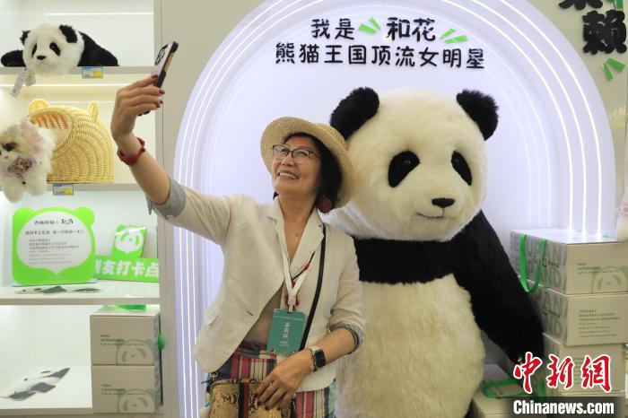 美國(guó)華視總裁楊蓮花與大熊貓文創(chuàng)產(chǎn)品合影。　王磊 攝