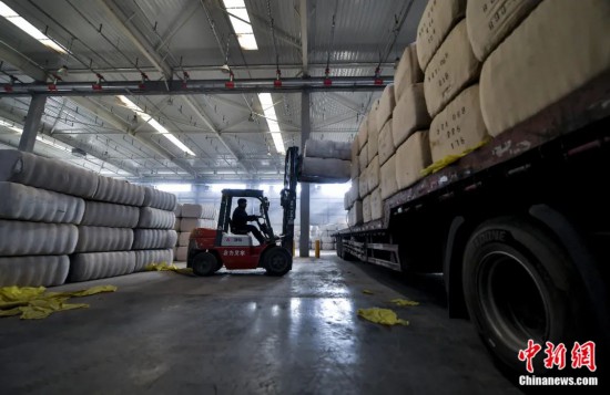 新疆喀什綜合保稅區(qū)，喀什啟路國際貿(mào)易有限公司的倉庫內(nèi)，工人正在裝載從塔吉克斯坦和烏茲別克斯坦進(jìn)口的棉花。劉新攝
