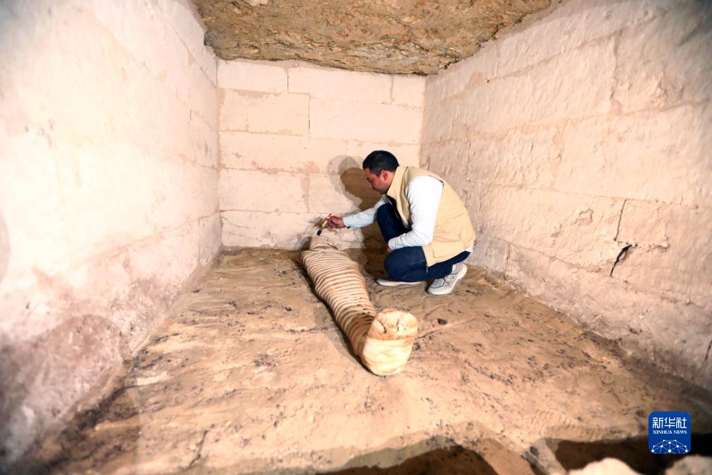 10月15日，在埃及明亞省考古現(xiàn)場，考古人員清理一座石鑿墓中的木乃伊。新華社發(fā)（艾哈邁德·戈馬攝）