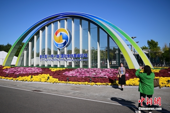 10月15日，北京，工作人員在國(guó)家會(huì)議中心外的第三屆“一帶一路”國(guó)際合作高峰論壇景觀布置前拍照留念。當(dāng)日，位于國(guó)家會(huì)議中心的第三屆“一帶一路”國(guó)際合作高峰論壇新聞中心啟動(dòng)試運(yùn)行。據(jù)悉，第三屆“一帶一路”國(guó)際合作高峰論壇將于10月17日至18日在北京舉行。<a target='_blank' href='/'><p  align=