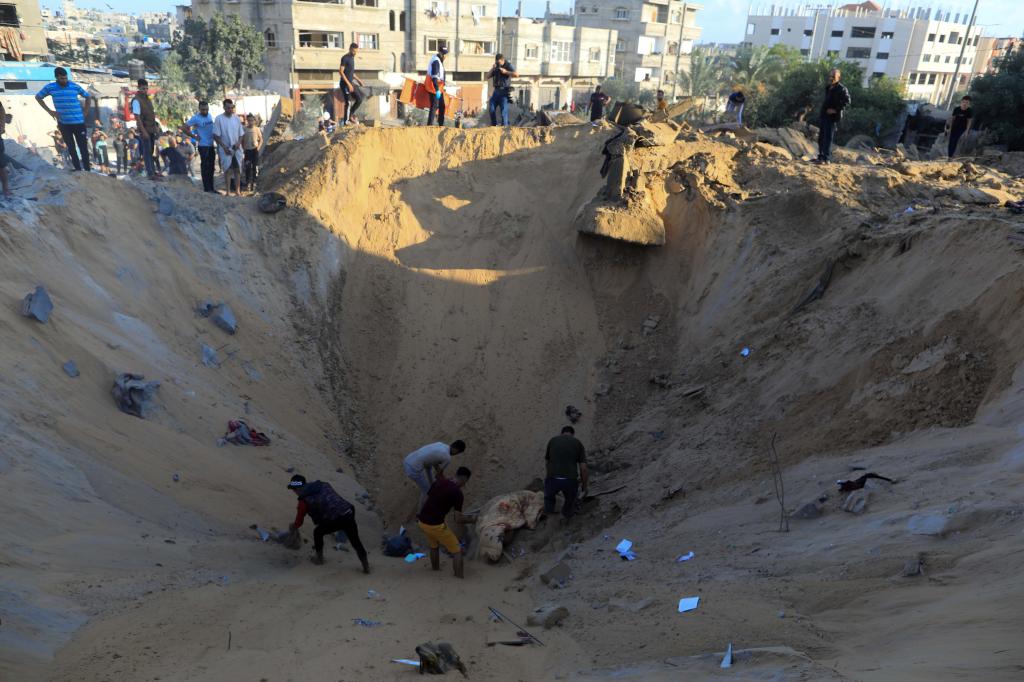 10月16日，在加沙地帶南部城市汗尤尼斯，人們在遭以色列襲擊后的建筑廢墟中救援傷者。 新華社發(fā)（亞西爾·庫迪 攝）