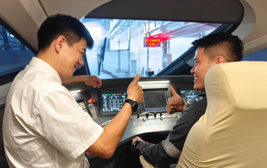 8月25日，在印度尼西亞萬(wàn)隆的雅萬(wàn)高鐵德卡魯爾動(dòng)車所內(nèi)，中國(guó)師傅穆振（左）在向印尼火車司機(jī)塞蒂亞萬(wàn)講解動(dòng)車組出庫(kù)前的上電作業(yè)。