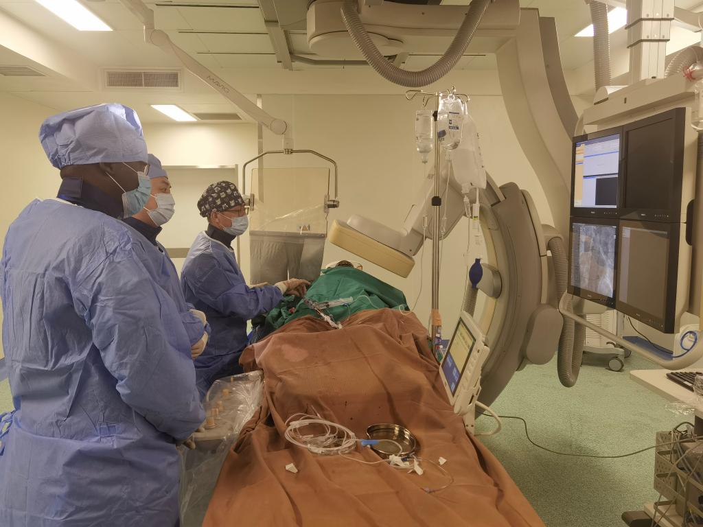 中國第29批援幾內(nèi)亞醫(yī)療隊隊員、首都醫(yī)科大學(xué)附屬北京天壇醫(yī)院心內(nèi)科副主任醫(yī)師王汝朋（右一）正在給患者做手術(shù)。（北京天壇醫(yī)院供圖）