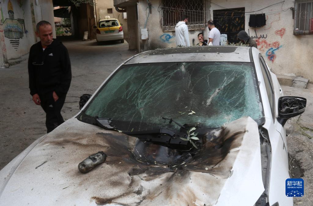 12月17日，在約旦河西岸城市圖勒凱爾姆附近的一處難民營，人們查看在沖突中損毀的車輛。新華社發(fā)（尼達(dá)爾·艾仕塔耶?dāng)z）