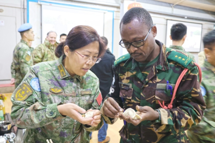 圖為維和官兵與外軍人員共同包餃子。胡光明攝
