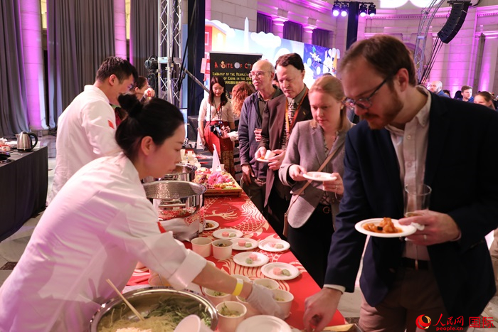 當(dāng)?shù)貢r間3月7日晚，華盛頓聯(lián)合車站廣場舉行駐美使團“使館主廚挑戰(zhàn)賽”。圖為當(dāng)?shù)孛癖娫谥袊古_前體驗中國美食。人民網(wǎng)記者 李志偉攝