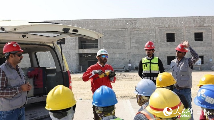 穆薩瓦爾(圖中紅衣人）現(xiàn)場演示工具操作規(guī)范。人民網(wǎng)記者 管克江攝