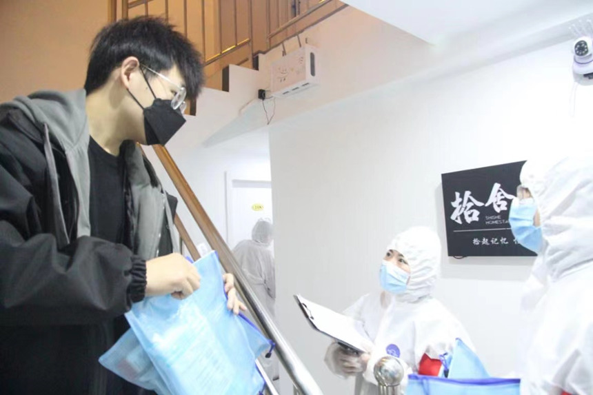 社區(qū)工作人員和志愿者身穿防護服上門送馬應龍大健康防疫包。徐帥攝