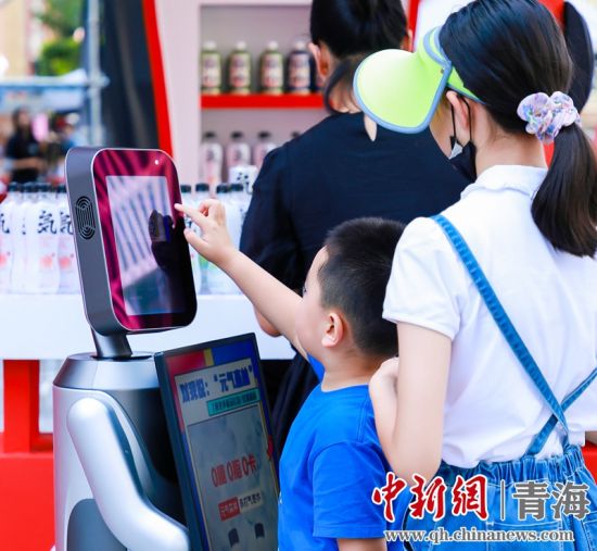 圖為一名小朋友正在和機(jī)器人“志愿者”進(jìn)行互動(dòng)。 沐聞 攝