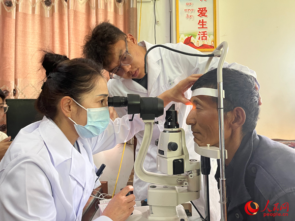 王紅英（左）和團隊成員為達熱村村民檢查眼睛。人民網(wǎng)記者 杜燕飛攝