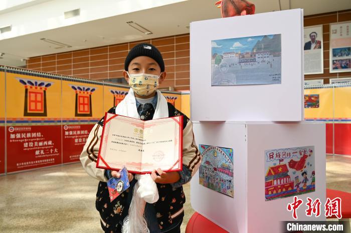 圖為一名獲獎學(xué)生與自己的繪畫作品合影?！≮w朗 攝
