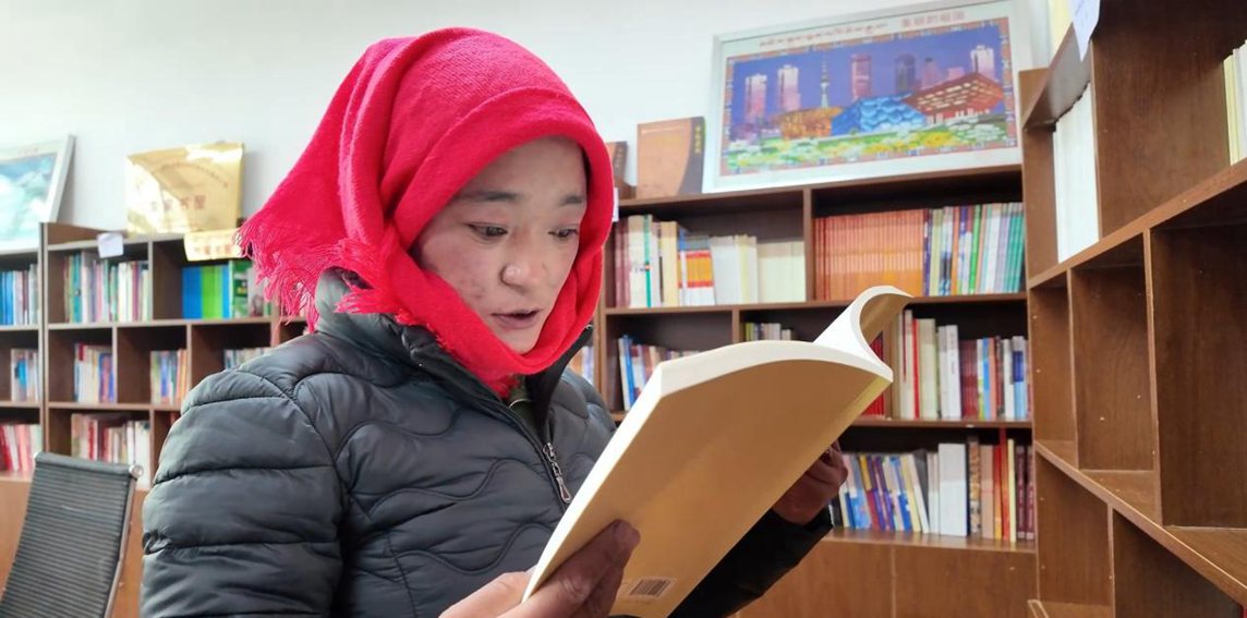 一名婦女正在認(rèn)真閱讀書籍。申扎縣融媒體中心供圖