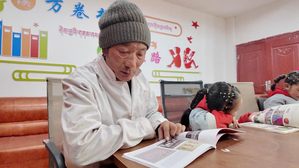 一位當(dāng)?shù)卮迕窈秃⒆觽冊谀良視堇锉M情享受閱讀時光。申扎縣融媒體中心供圖
