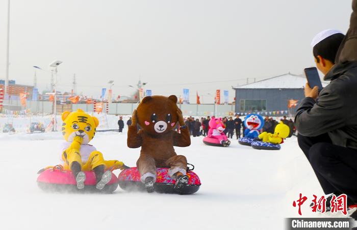 圖為臨夏市南龍鎮(zhèn)馬家莊村舉辦的鄉(xiāng)村文化旅游節(jié)上，游客穿著卡通服裝在體驗(yàn)雪上飛碟項(xiàng)目。近年來(lái)，臨夏州形成了“春賞花、夏避暑、秋摘果、冬玩雪”的全季節(jié)旅游產(chǎn)品體系。(資料圖) 高展 攝