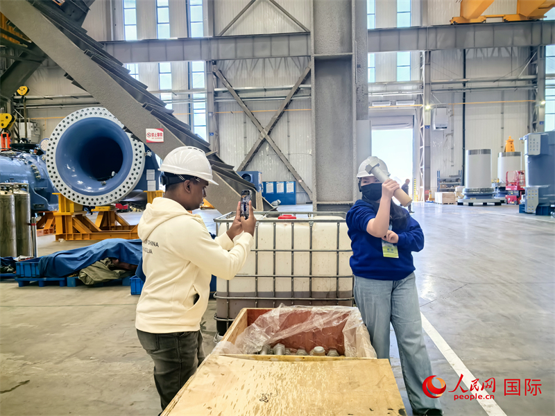 外媒記者掂量廠房內(nèi)的巨型螺栓。人民網(wǎng) 楊春燕攝