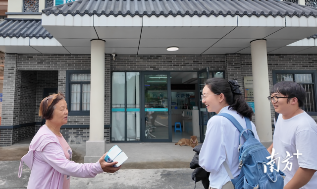 公共服務(wù)組成員王櫻潔（中）和張龍（右）在崖口村衛(wèi)生室前跟村民打招呼。