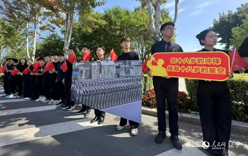 沈陽市人民廣場上，大學(xué)生們手持閱兵的圖片，告慰英烈。人民網(wǎng)記者 周頌雪攝