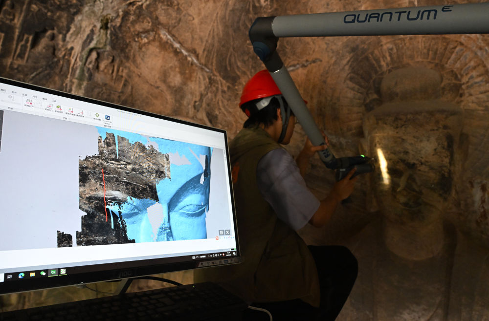 2025年4月9日，武漢大學(xué)文化遺產(chǎn)智能計算實驗室團隊成員在魏字洞使用關(guān)節(jié)臂掃描儀對佛像進行數(shù)字化掃描。圖片來源新華社