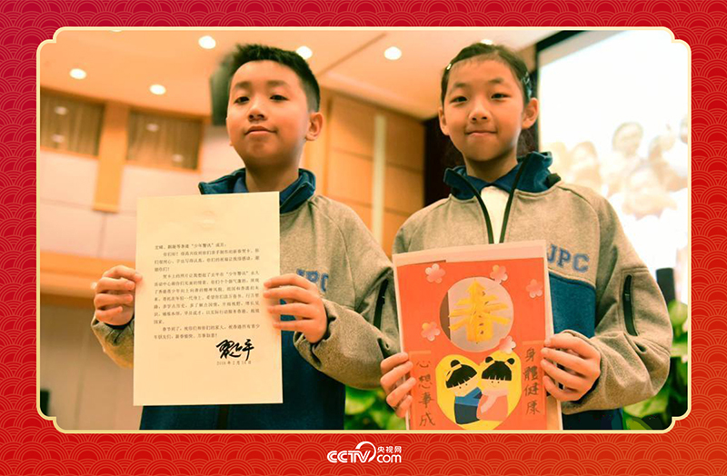 圖為香港“少年警訊”成員郭宏晞（左）展示習(xí)主席回信、羅顥凝（右）展示送給習(xí)主席的賀卡并合影。