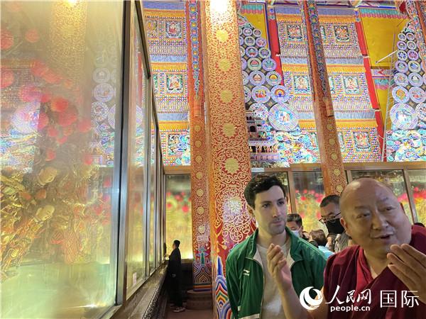 7月25日，省級(jí)非物質(zhì)文化遺產(chǎn)項(xiàng)目塔爾寺酥油花的代表性傳承人朋措堅(jiān)參（右）在塔爾寺酥油花館講解酥油花的制作過程。人民網(wǎng) 謝瑩攝
