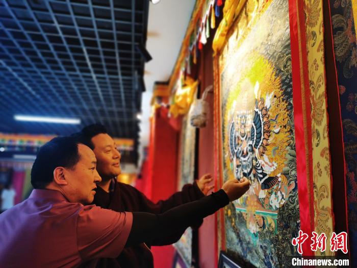 圖為久美尖措展示唐卡作品?！?zhí)砀?攝