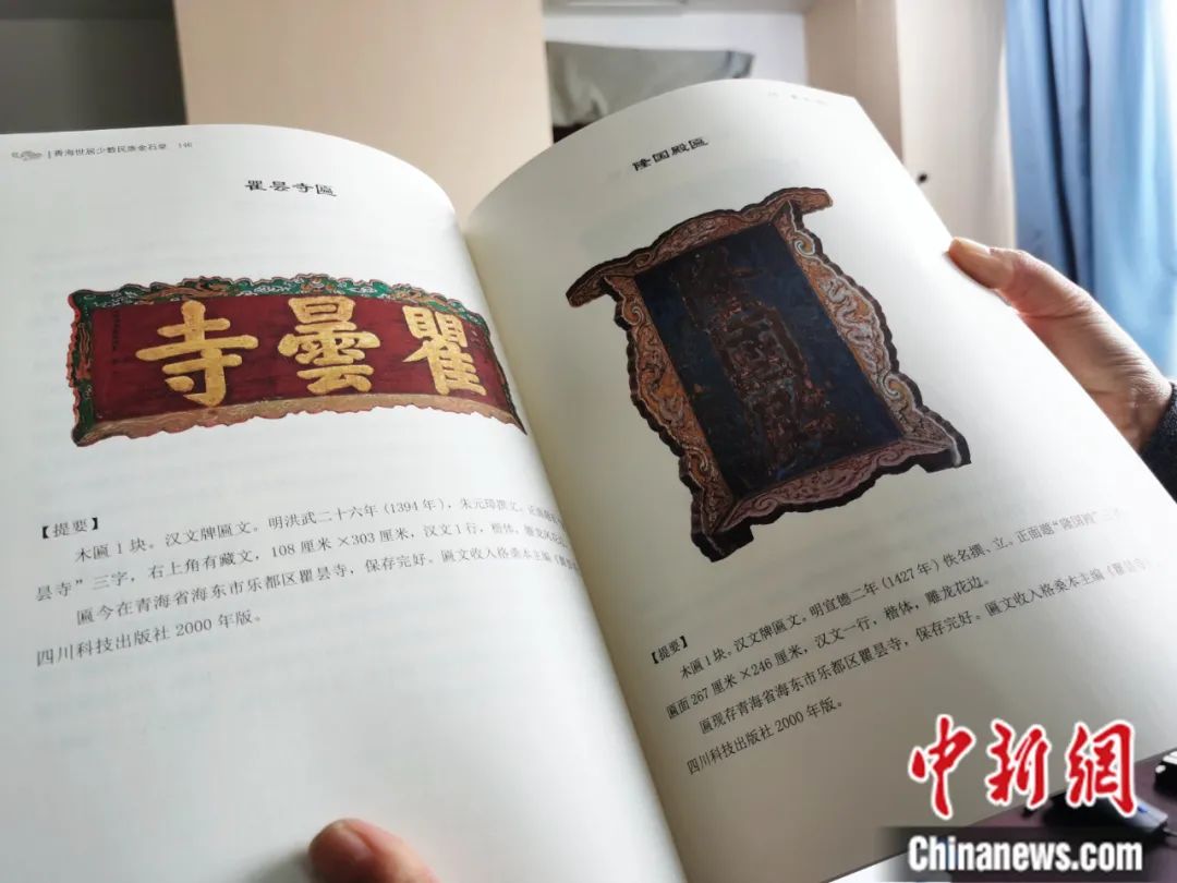 古籍保護(hù)人員展示介紹明代朱元璋撰寫(xiě)的青海瞿曇寺匾(左)的出版書(shū)籍。張?zhí)砀?攝