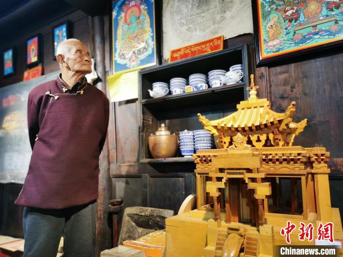 圖為古堡內(nèi)的藝人桑杰展示自己的雕刻作品?！?zhí)砀?攝