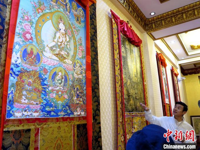 圖為完德尖措展示熱貢龍樹畫苑內(nèi)的唐卡?！?zhí)砀?攝