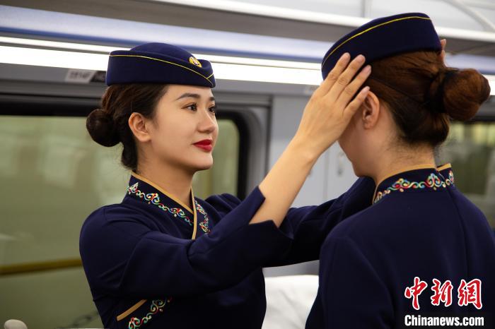 圖為青藏鐵路西格段“復(fù)興號”動車組乘務(wù)員互相整理新制服?！±罾?攝