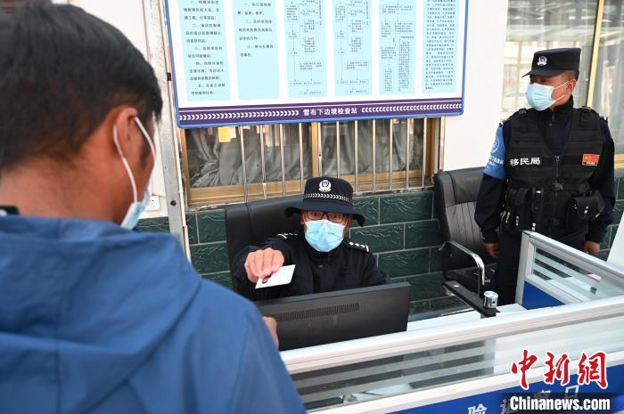 圖為移民管理警察登記完身份信息后將證件歸還給行人?！≮w朗 攝