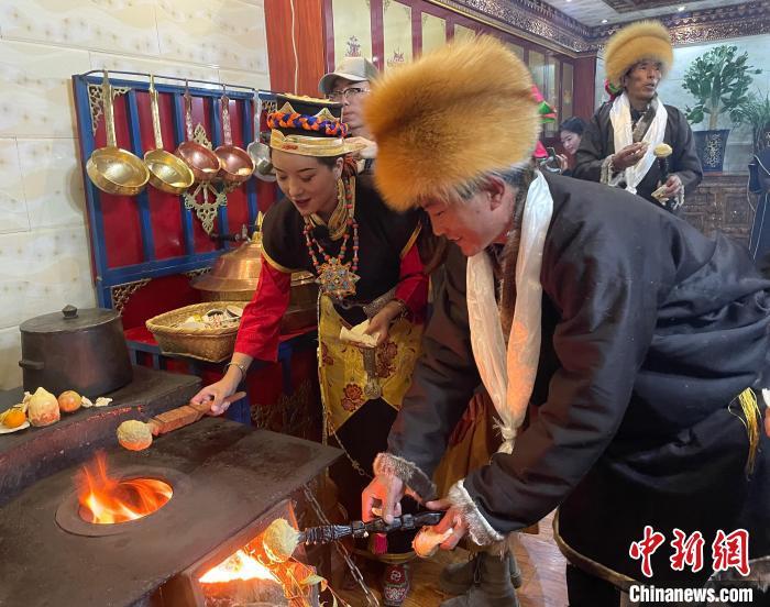 圖為人們在火上烤節(jié)日美食“結(jié)達”?！∪轿木?攝