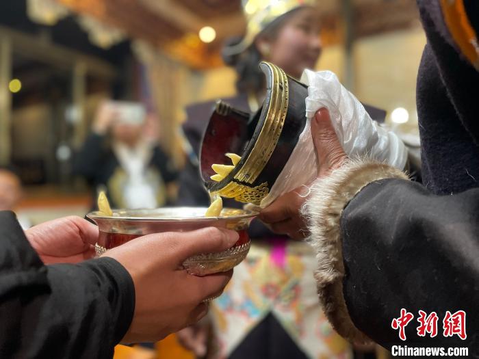 圖為主人在碗中斟滿青稞酒?！∪轿木?攝