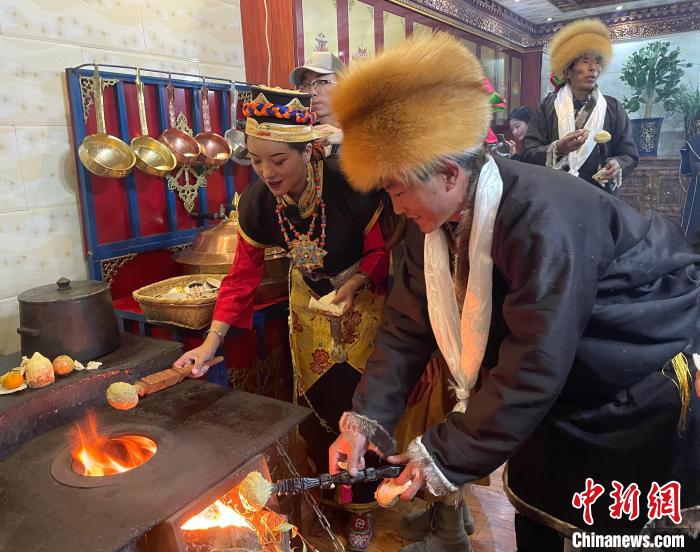 圖為人們在火上烤節(jié)日美食“結(jié)達”?！∪轿木?攝