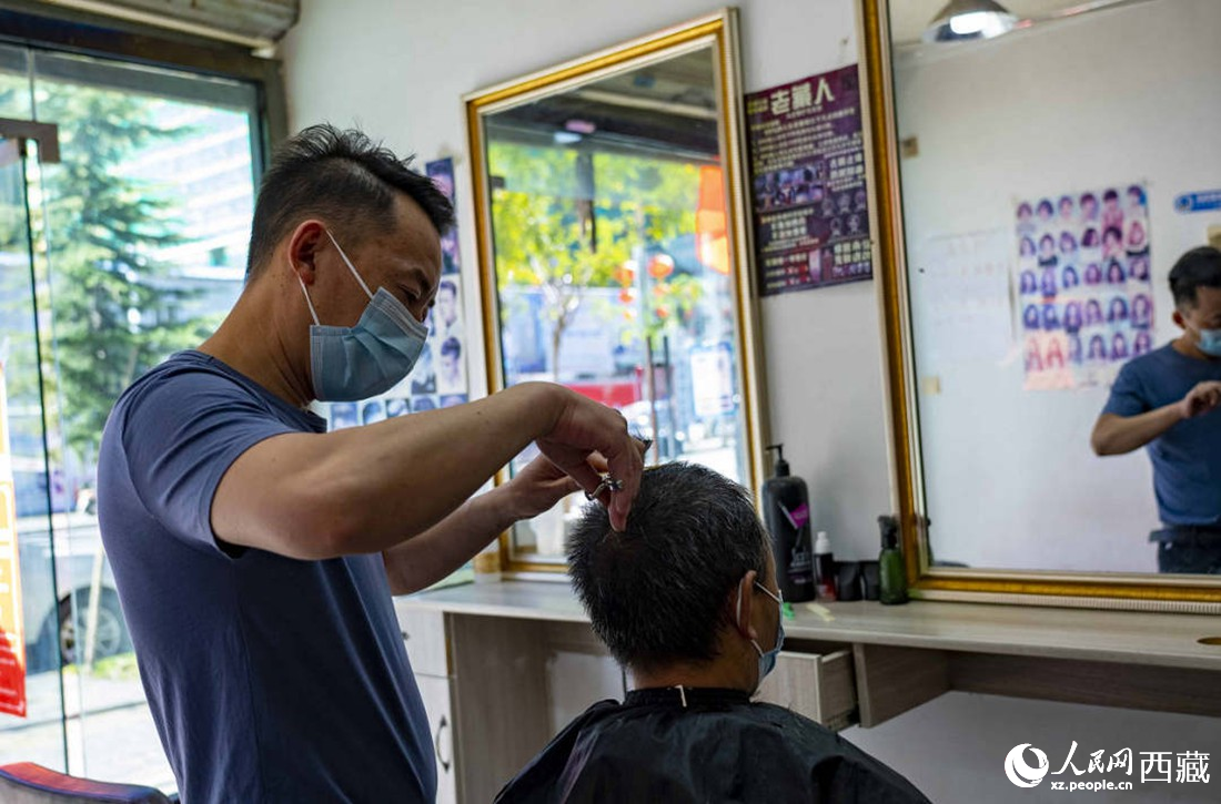理發(fā)店老板為顧客理發(fā)。次仁羅布 攝