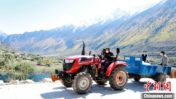 圖為工作人員將把加工完成的糌粑運(yùn)送至村民手中?！〖卫杩h融媒體中心供圖