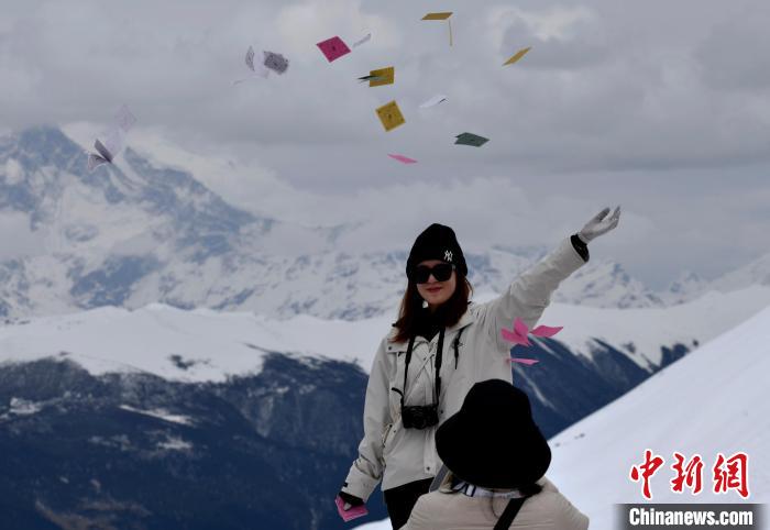 圖為5月14日，游客在西藏林芝色季拉山觀景臺拋灑“隆達(dá)”(風(fēng)馬旗，藏族民眾的一種祈福方式)?！±盍?攝