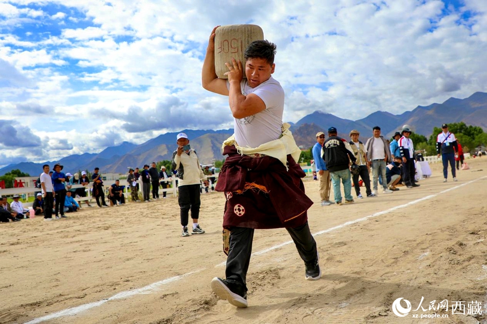 來自拉薩市當(dāng)雄縣的牧民選手將一塊150斤重的石頭扛在肩上飛奔。