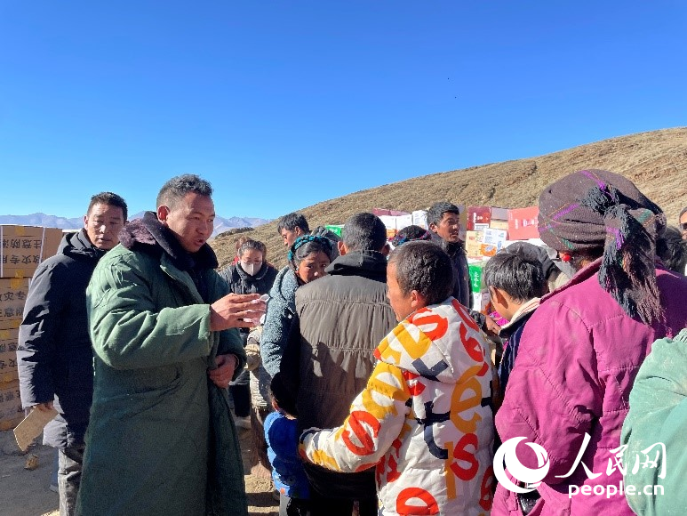 定日縣公安局干警頓珠次仁（左二）正在協(xié)助分發(fā)物資。人民網(wǎng)記者 郝潔攝