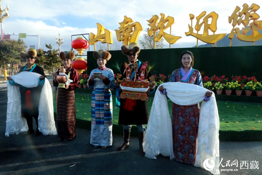 扎西曲登社區(qū)的居民在“山南歡迎您”標志前，手持潔白哈達和切瑪，列隊迎接來自區(qū)內(nèi)外的游客，用最隆重的禮儀開啟一場沉浸式藏歷新年民俗體驗之旅。人民網(wǎng)記者 吳雨仁攝