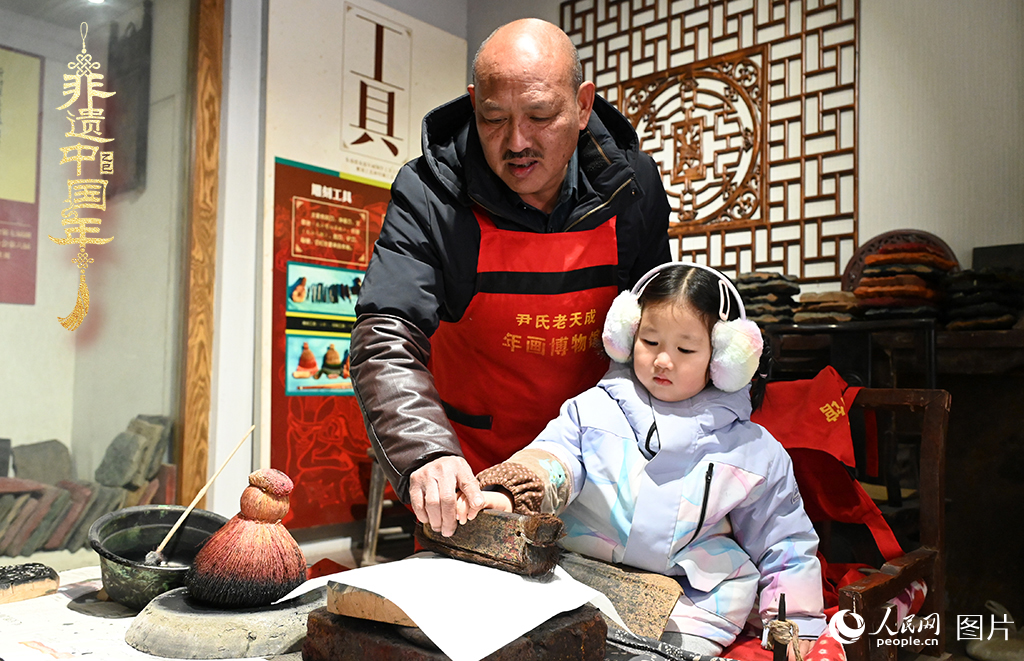 2025年1月27日，河南開封朱仙鎮(zhèn)木版年畫藝人尹國法指導小朋友研習年畫印制技藝。朱仙鎮(zhèn)木版年畫源自漢唐壁畫藝術(shù)，是中國木版年畫的鼻祖。2006年5月20日，朱仙鎮(zhèn)木版年畫經(jīng)國務(wù)院批準列入第一批國家級非物質(zhì)文化遺產(chǎn)名錄。人民網(wǎng)記者 王玉興攝