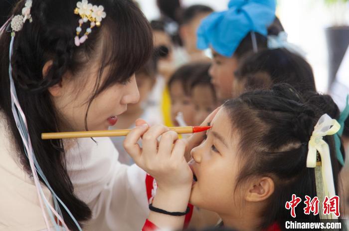 圖為老師在孩子們額頭上點(diǎn)上雄黃，驅(qū)邪辟禍?！《^生 攝