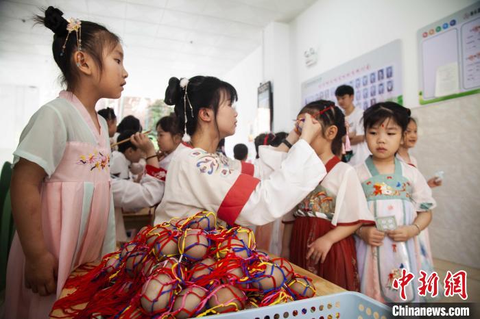 圖為幼兒園的老師們穿上漢服為小朋友們戴上彩蛋，寓意著幸福安康?！《^生 攝